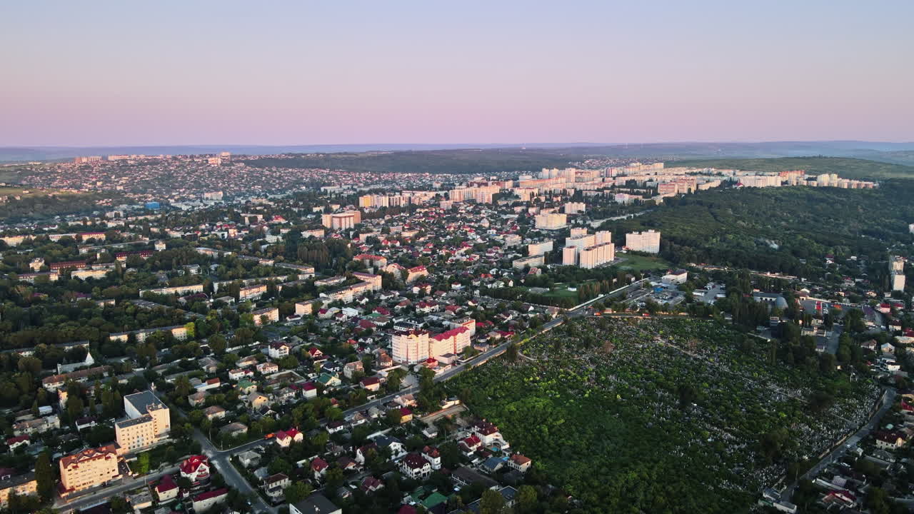 Aerial drone view of Chisinau at sunrise. Multiple buildings, trees, parks, roads with cars. Moldova