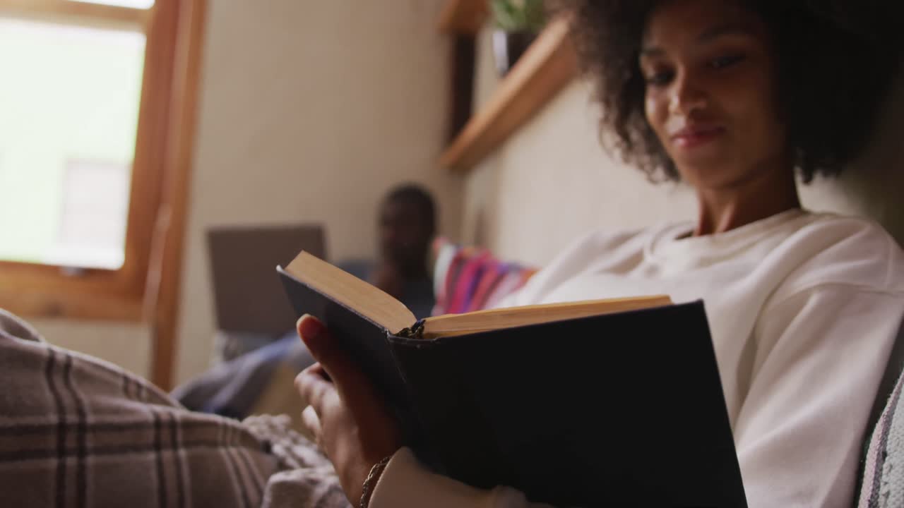 mujer de raza mixta leyendo en la sala de estar