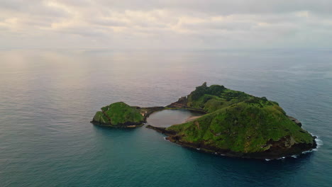 pintoresca isla verde tomada aérea. drone volando sobre el vasto océano en un día nublado