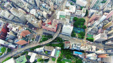 traffic passing through a car park building in downtown hong kong, with city mega buildings, aerial view