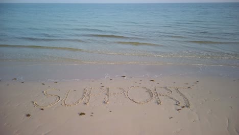 static shot of support written in the sand on a beach showing the horizon and the ocean