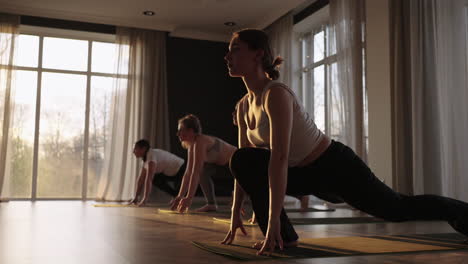 young caucasian sporty people practicing yoga lesson with instructor. caucasian group of women exercising healthy lifestyle in fitness studio. sport activity gymnastics class. slow motion.