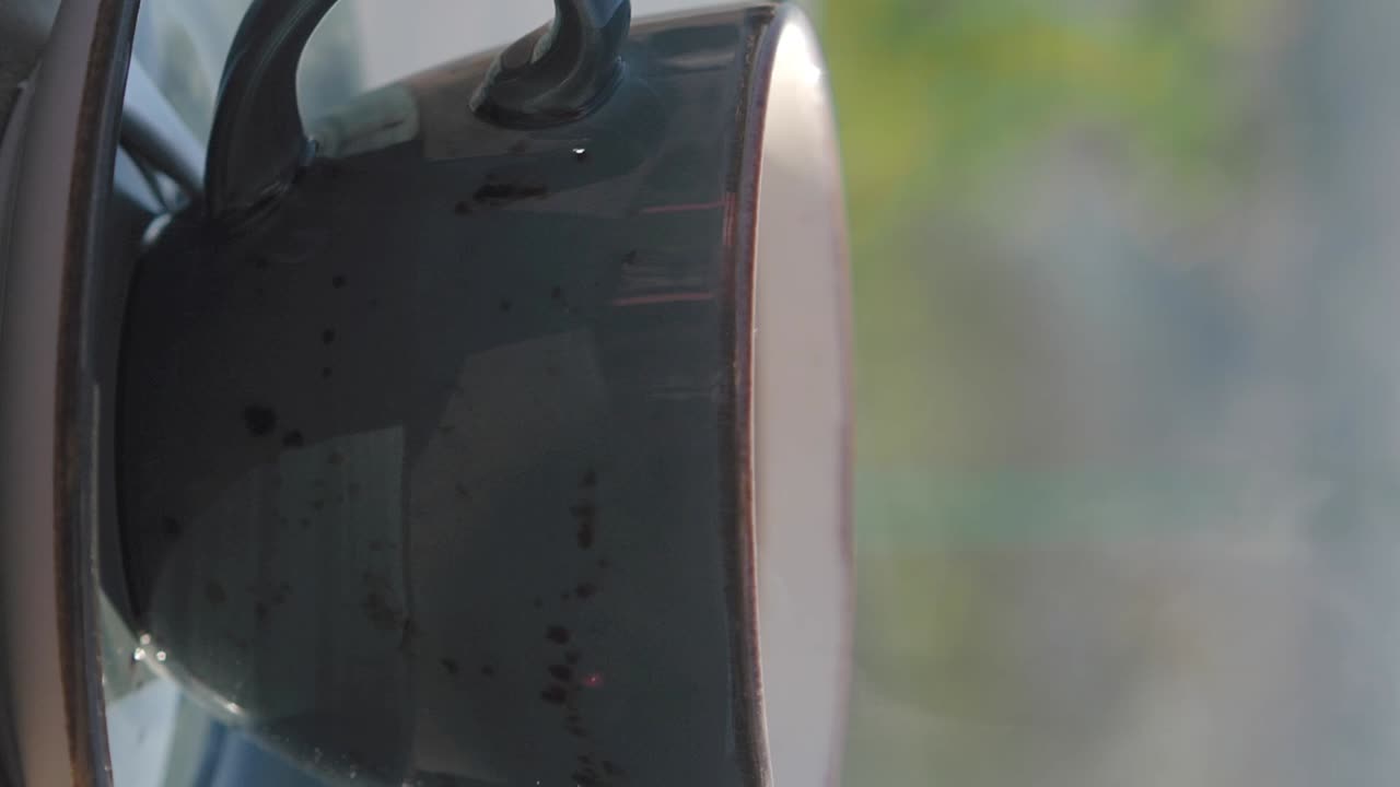 A dark ceramic mug in close-up with a soft, blurry background