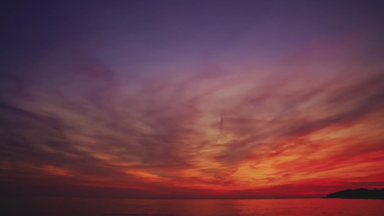 cinemagraph bucle de video sin problemas de una puesta de sol roja vibrante en una remota playa de arena costera de la toscana natural en italia con un cielo dramático y vistas panorámicas al mar. agua azul y turquesa en el pintoresco lugar de vacaciones turísticas de la naturaleza.