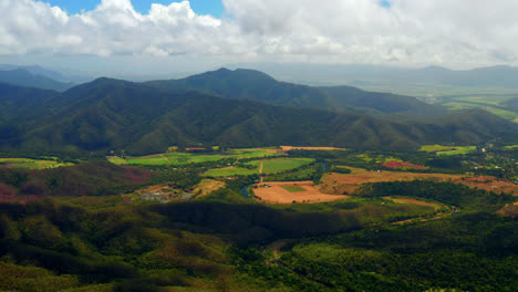 fluffy white clouds over rural fields and lush green mountains at summer in atherton, tablelands, qld, australia