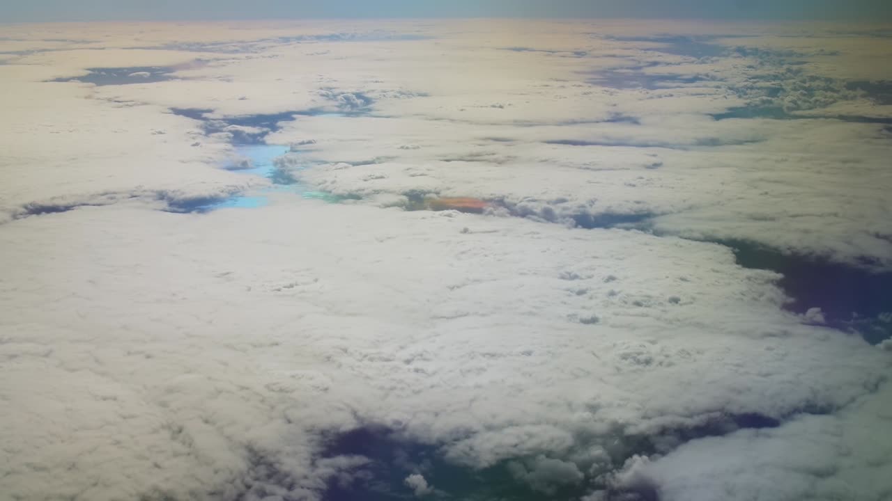 Big flat clouds covering multicolor water on planet from above