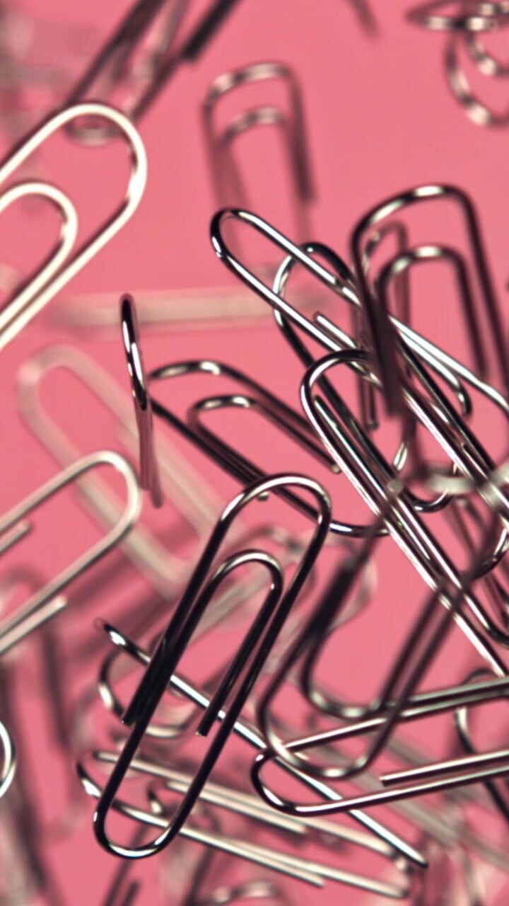 Scatto macro di graffette argentate su uno sfondo rosa