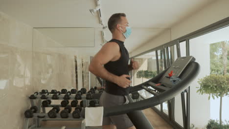 l'atleta maschio con maschera facciale usa il tapis roulant in palestra