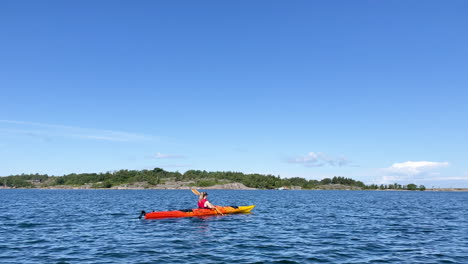 woman on a kayak paddling towards island in open water