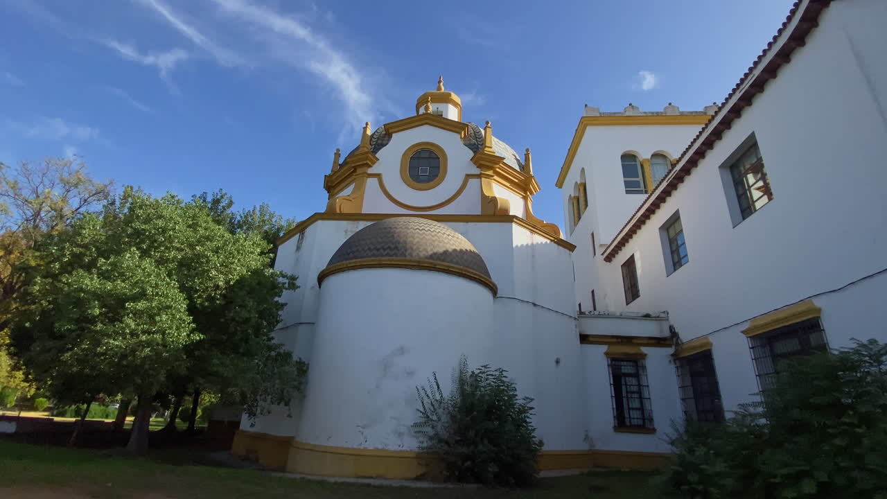 Seville'de uzun kuleli ve süslü balkonlu barok kilise cephesi, masmavi bir gökyüzüne karşı yükseliyor