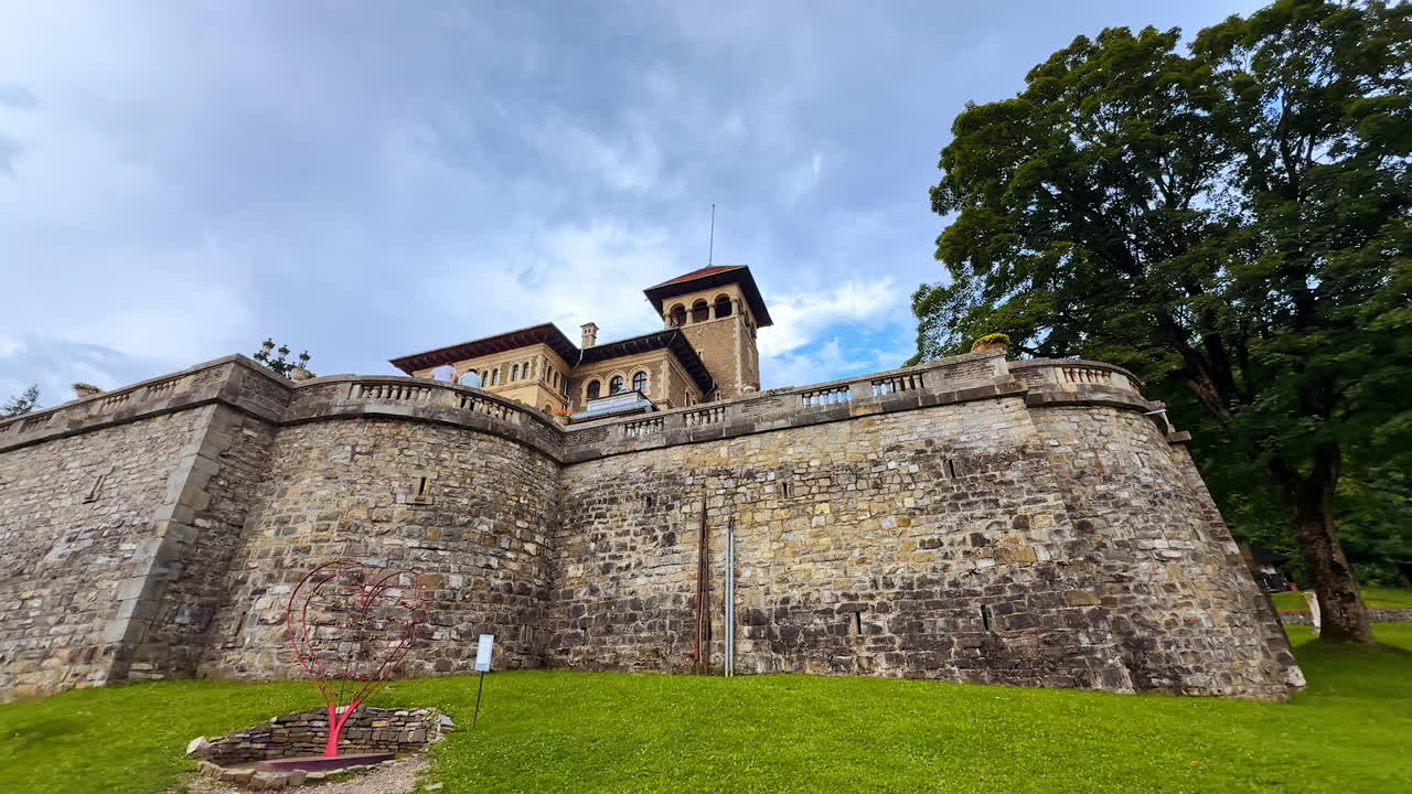 Busteni, Romania, 17 July 2025: Approaching a heart sculpture with padlocks near the stone wall. Territory of Cantacuzino Castle in Busteni, Romania