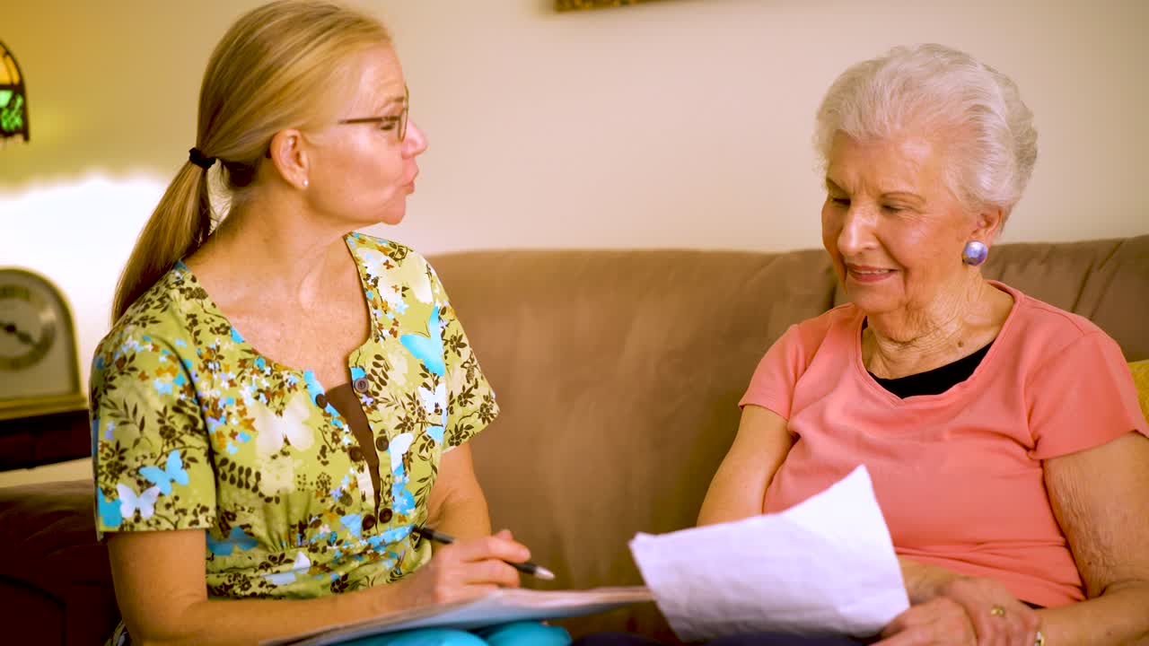 Closeup of elderly woman and home healthcare nurse laughing and going over paperwork