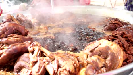 cocinando patas de cerdo en una gran olla de estofado.