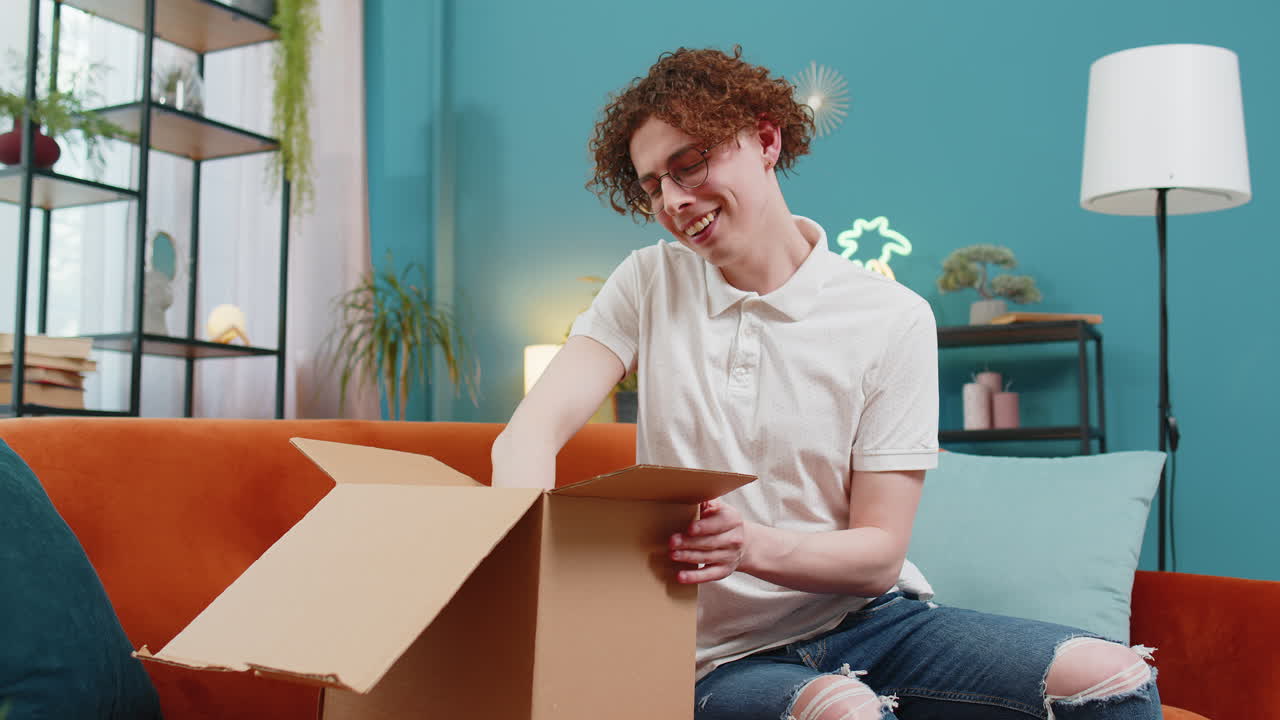 Happy customer man unpacking delivery parcel opening cardboard box receiving purchase gift at home