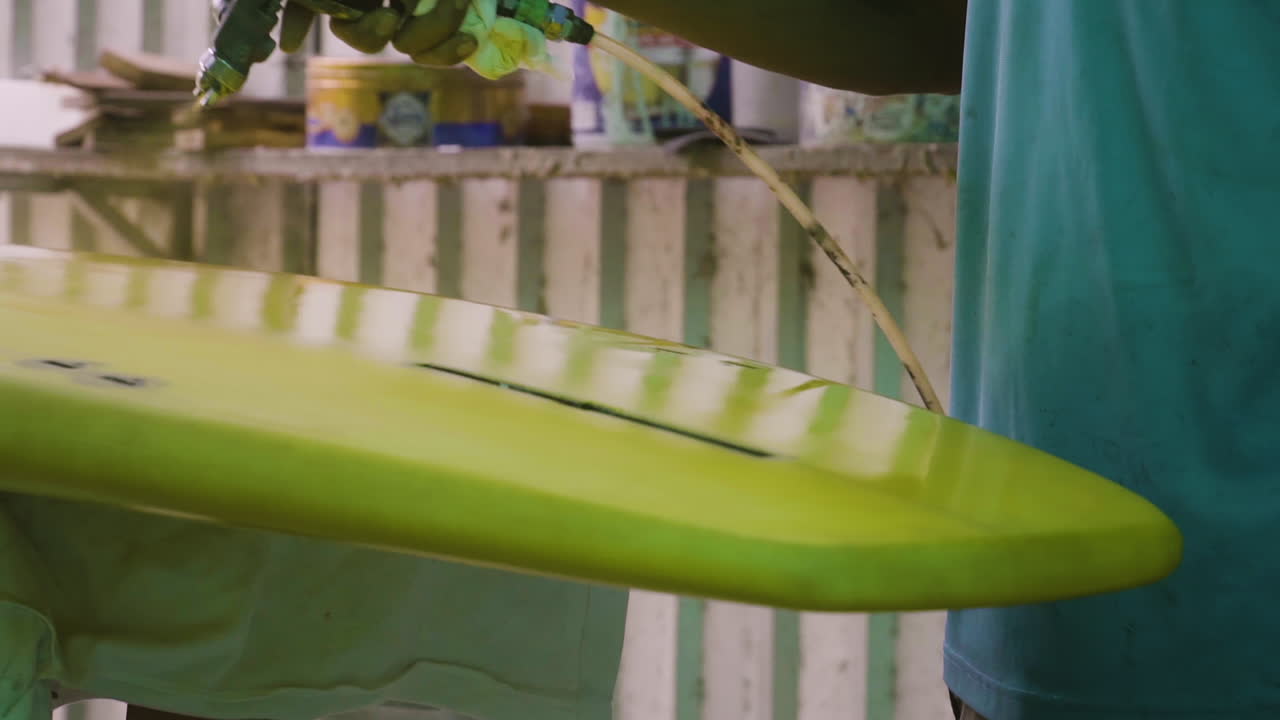 스프레이 화가로 서핑보드 녹색을 그리는 검은 손 클로즈업