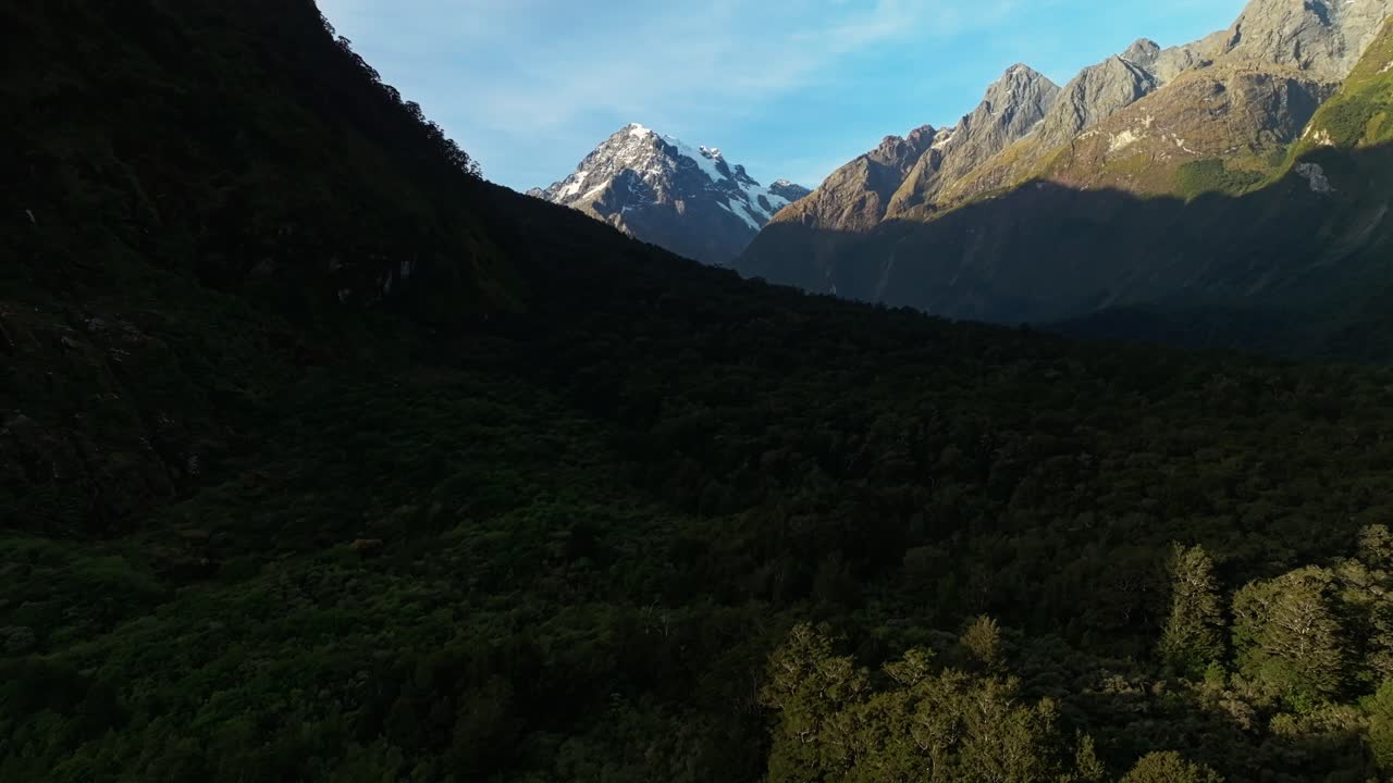 valle montañoso sombreado con picos rocosos cubiertos de nieve en el sonido de milford
