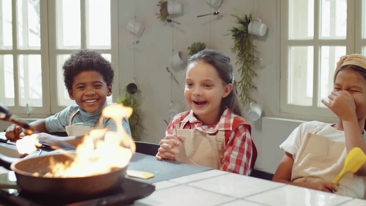 Bambini entusiasti che guardano lo chef flambare un piatto a una masterclass di cucina