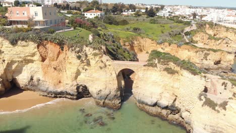 roman style bridge connecting rock outcrops of lagos shoreline, algarve, portugal - aerial point of interest panoramic shot