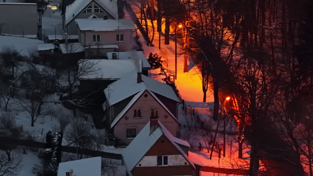 Landsbyhuse i skumringen, vinteraften, der skaber en hyggelig atmosfære med orange glød.