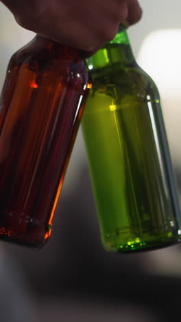 black sports fan carries bottles of cool beer to table with chips against blurry friends in apartment closeup. happy evening and watching football