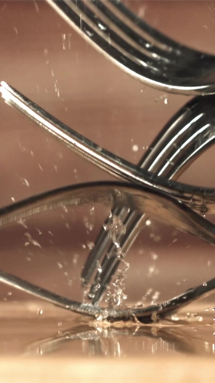 Silver Forks Splashing into Water in Slow Motion