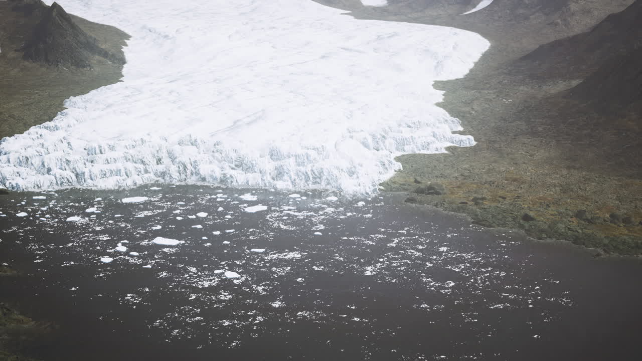 Glacier melting into dark water body with rocky landscape in background