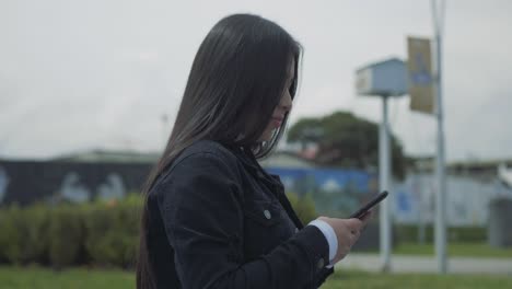 Mujer-Hispana-De-Cabello-Negro-Escribiendo-En-Su-Teléfono-Y-Mirando-Hacia-Arriba