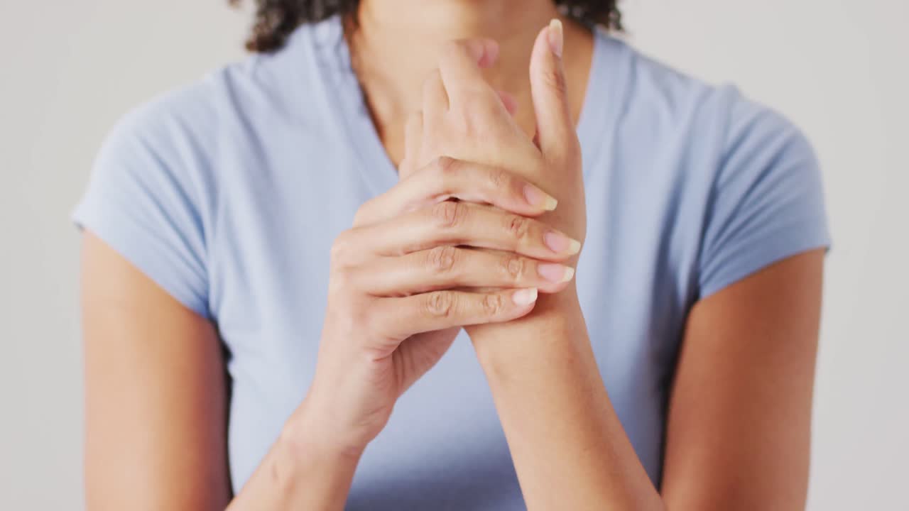 video de una mujer biracial tocando su mano sobre un fondo blanco