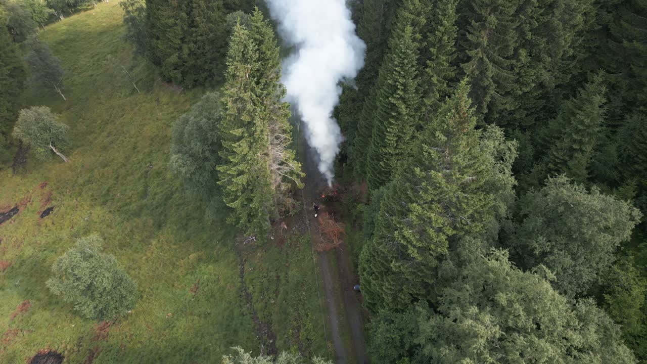 los agricultores alimentan una hoguera de residuos en un camino con cenizas volando por todas partes en vik i sogn, noruega