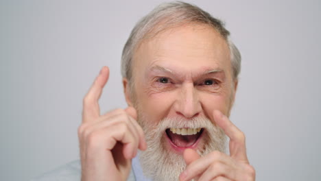 joyful man grimacing in photo studio. old guy making funny face indoors.