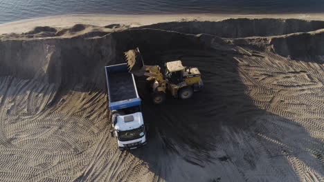 aerial view of excavator loading dump truck with dirt/sand