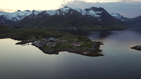 Fantastic-aerial-shot-in-orbit-over-a-small-town-located-in-the-Austnesfjorden-fjord-and-its-large-mountains-at-golden-hour