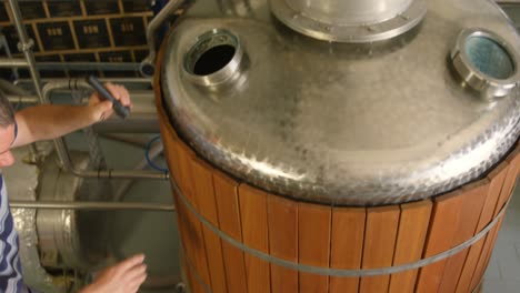 male worker examining a distillation tank 4k