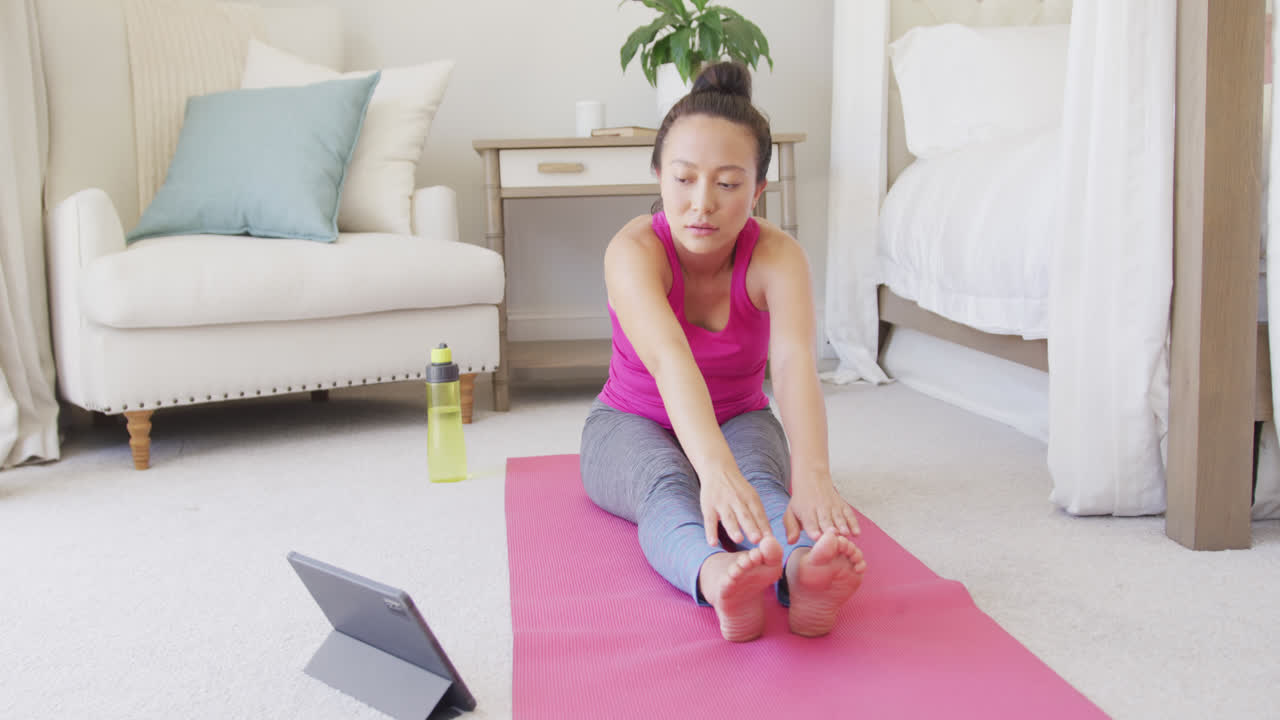 mujer asiática feliz haciendo yoga y estiramiento en el dormitorio, en cámara lenta