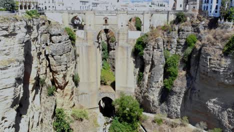 Drone-shot-reversing-out-from-under-the-bridge-in-Ronda,-Spain