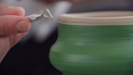 close-up of potter's hands working on a green ceramic bowl