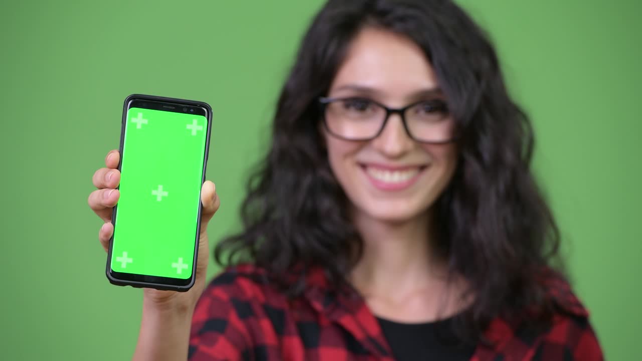 Face of young happy hipster woman smiling while showing phone