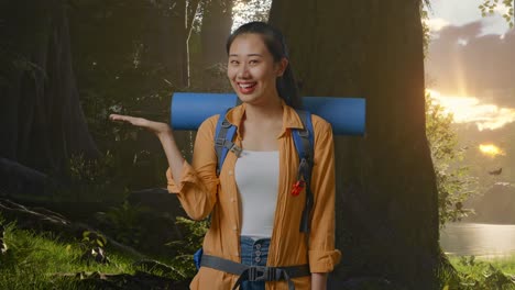 asian female hiker with mountaineering backpack smiling and pointing to side while exploring forest nature