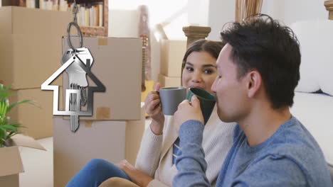 animation of silver house key and key fob over diverse couple drinking tea at new home