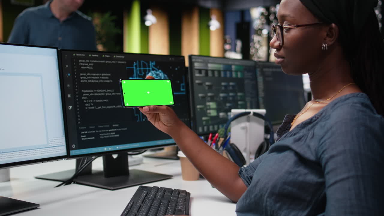Female Programmer Holding Green Screen Smartphone While Coding