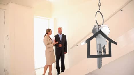 House-keys-and-key-fob-hanging-with-people-viewing-house-in-the-background