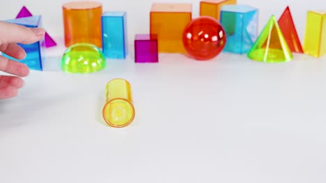 vibrant geometric shapes roll across a white surface, demonstrating motion and interaction in a brightly lit environment