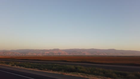 driving to los angeles with mountains in the valley in the distance at sunset