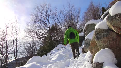 Hombre-Vestido-Con-Un-Anorak-Verde-Caminando-Por-Un-Sendero-De-Montaña-Entre-Rocas