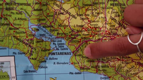 person pointing with her finger a printed geographic map of costa rica, central america