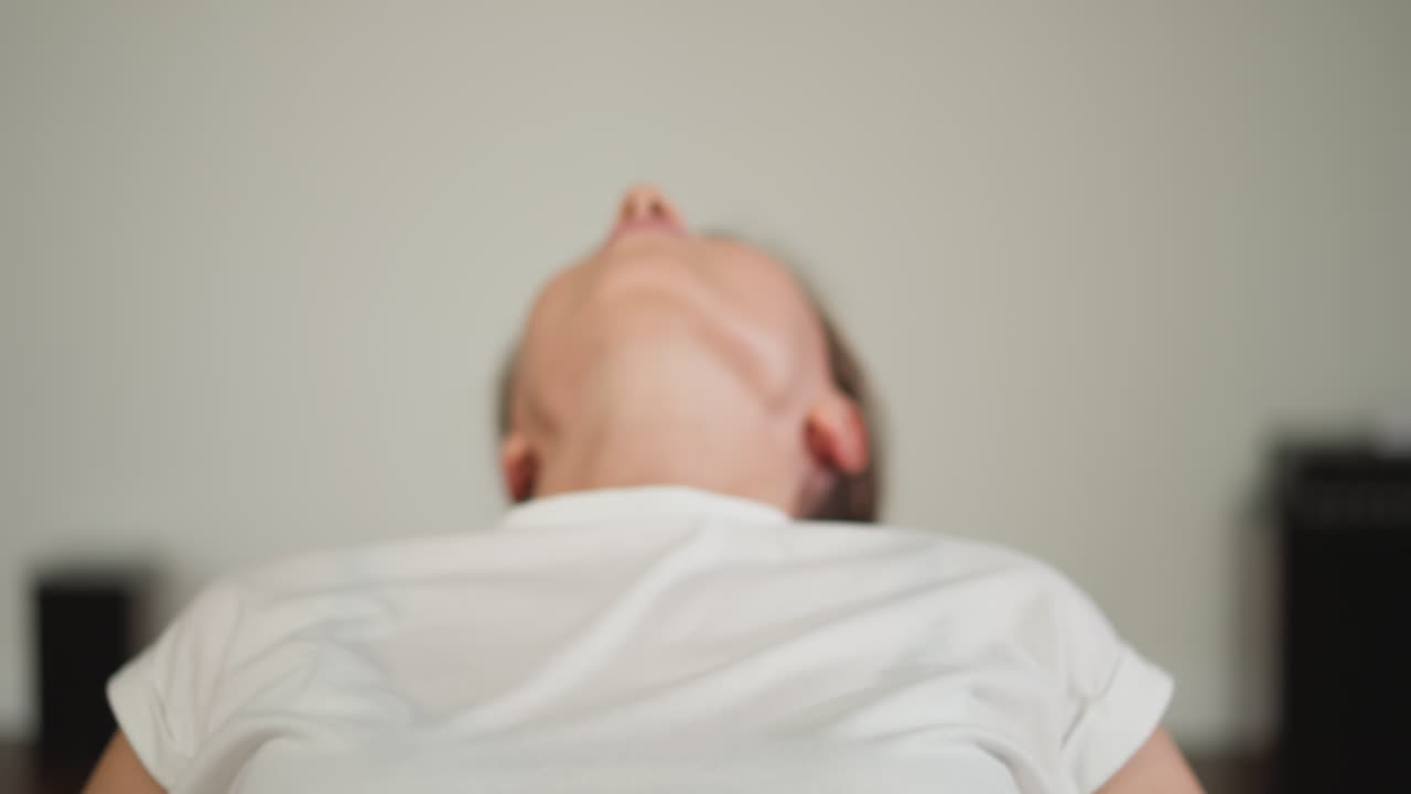 고급스러운 여성은 집에서 피트니스 공을 고 있습니다. 비어있는 배를 가진 평온한 운동 여성은 개인 운동 구역에서 운동을 즐니다. 고향 피트니스 구역