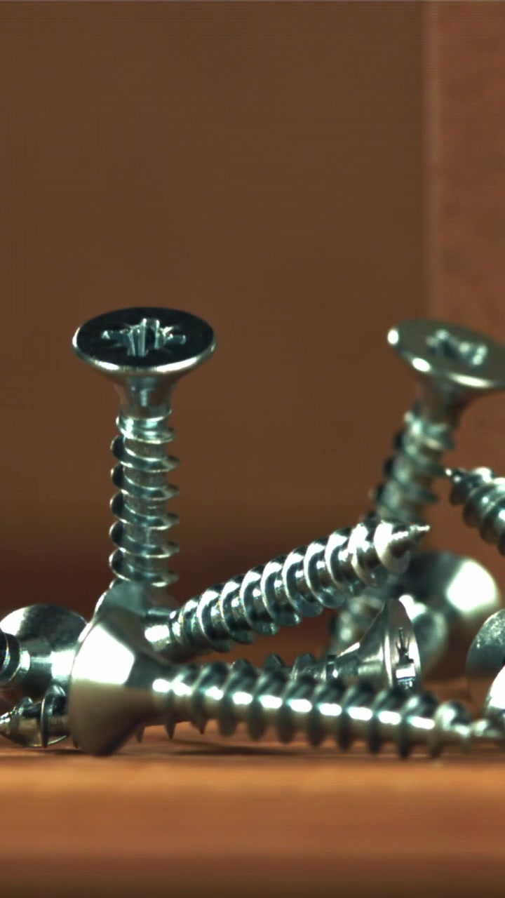 Slow Motion Close-up of Screws Falling onto a Wooden Surface