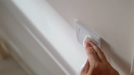 limpieza de un interruptor de luz de pared con un pañuelo