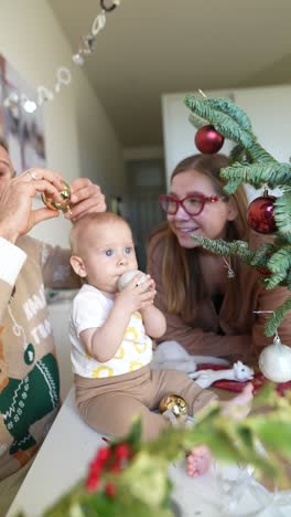 family decorating the christmas tree with baby