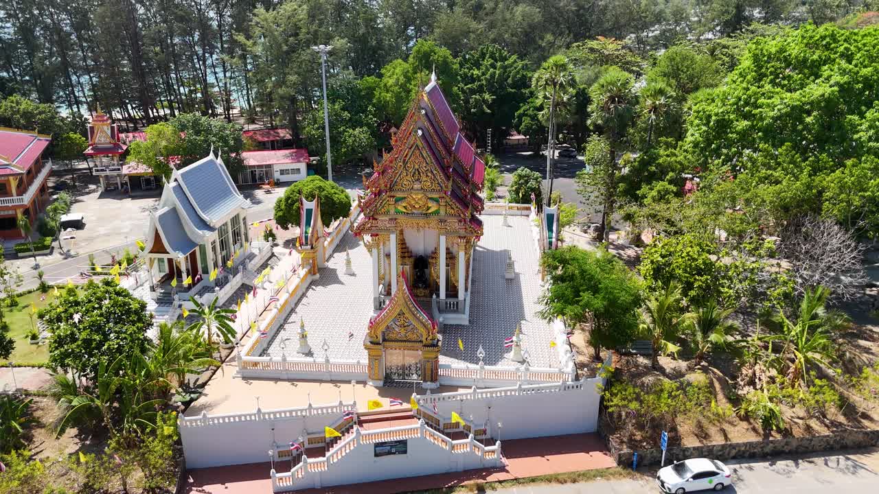 imágenes de drones capturan el templo de wat nai harn rodeado de exuberante vegetación en phuket, tailandia, bajo la luz del día.